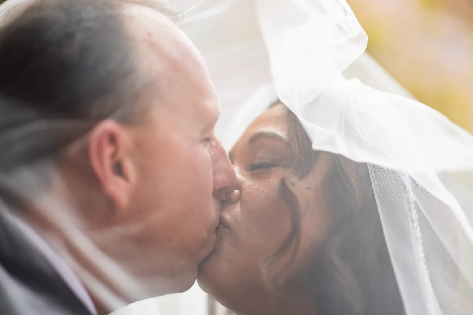 Bride and groom sharing a kiss beneath her veil in soft, warm light at Red Rock Canyon