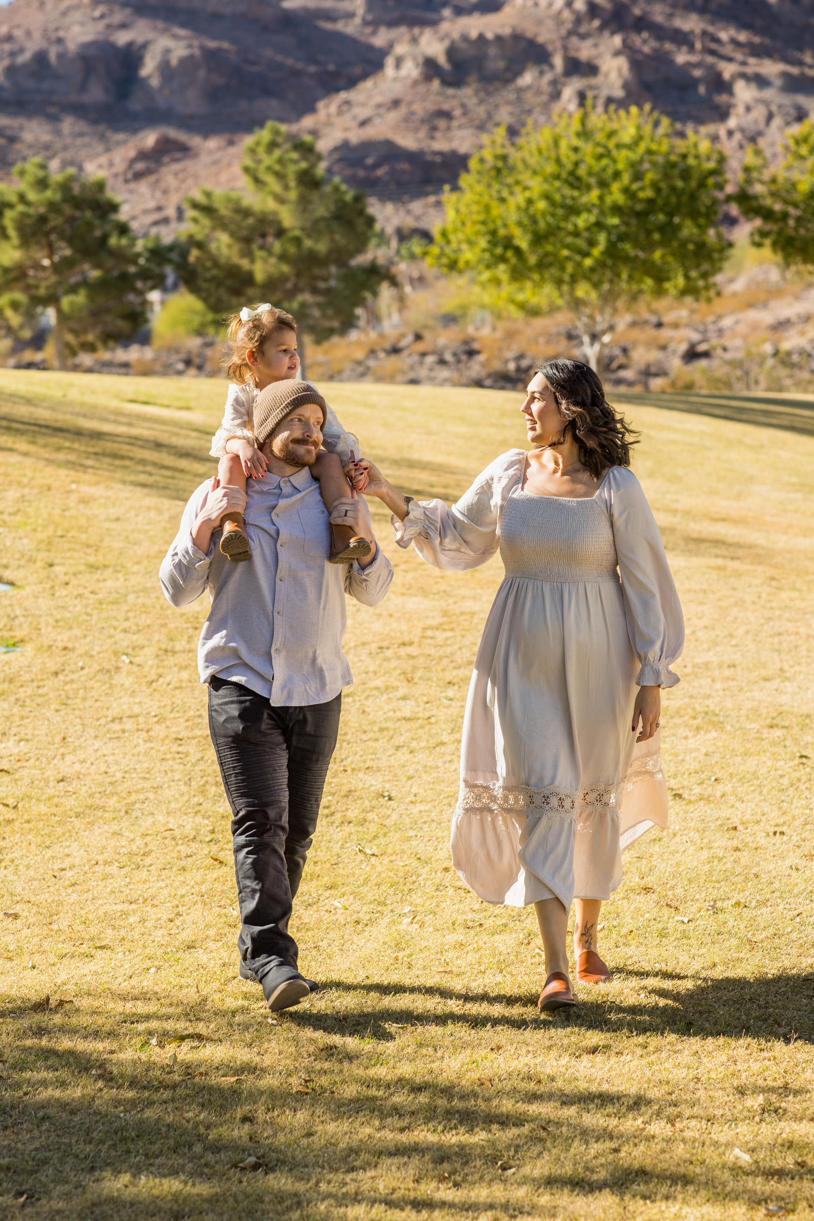 Mother and daughters walking through an open field during a Henderson family session