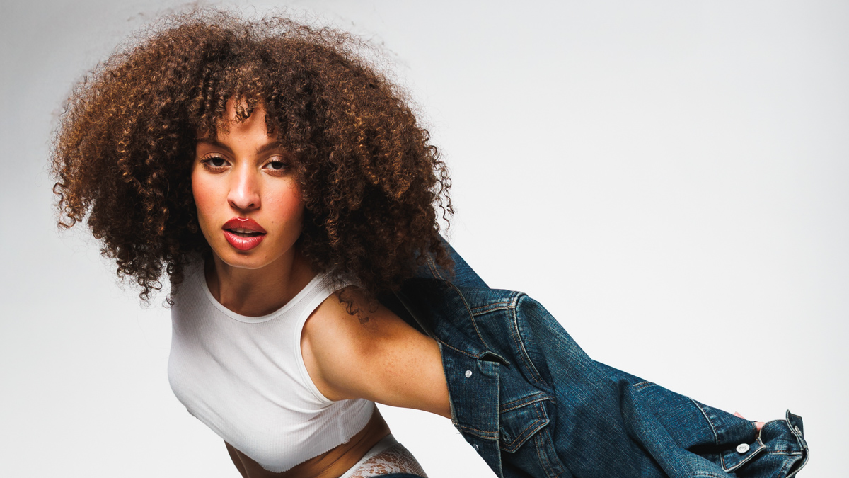 Studio portrait of a woman wearing a white top and denim jacket.