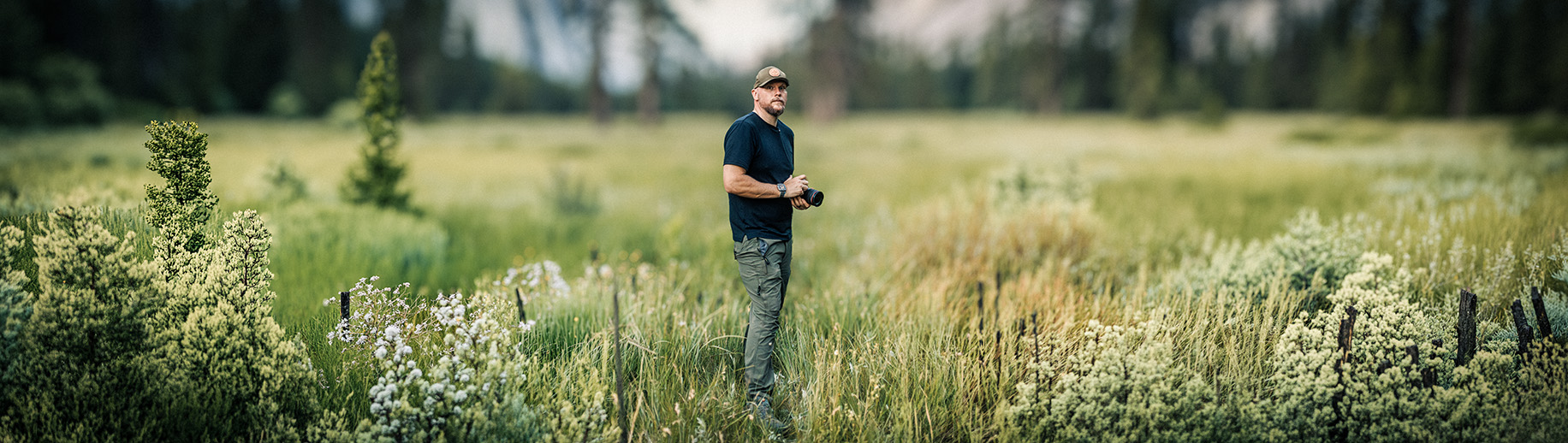 Joseph Blake standing in a wide meadow with his camera