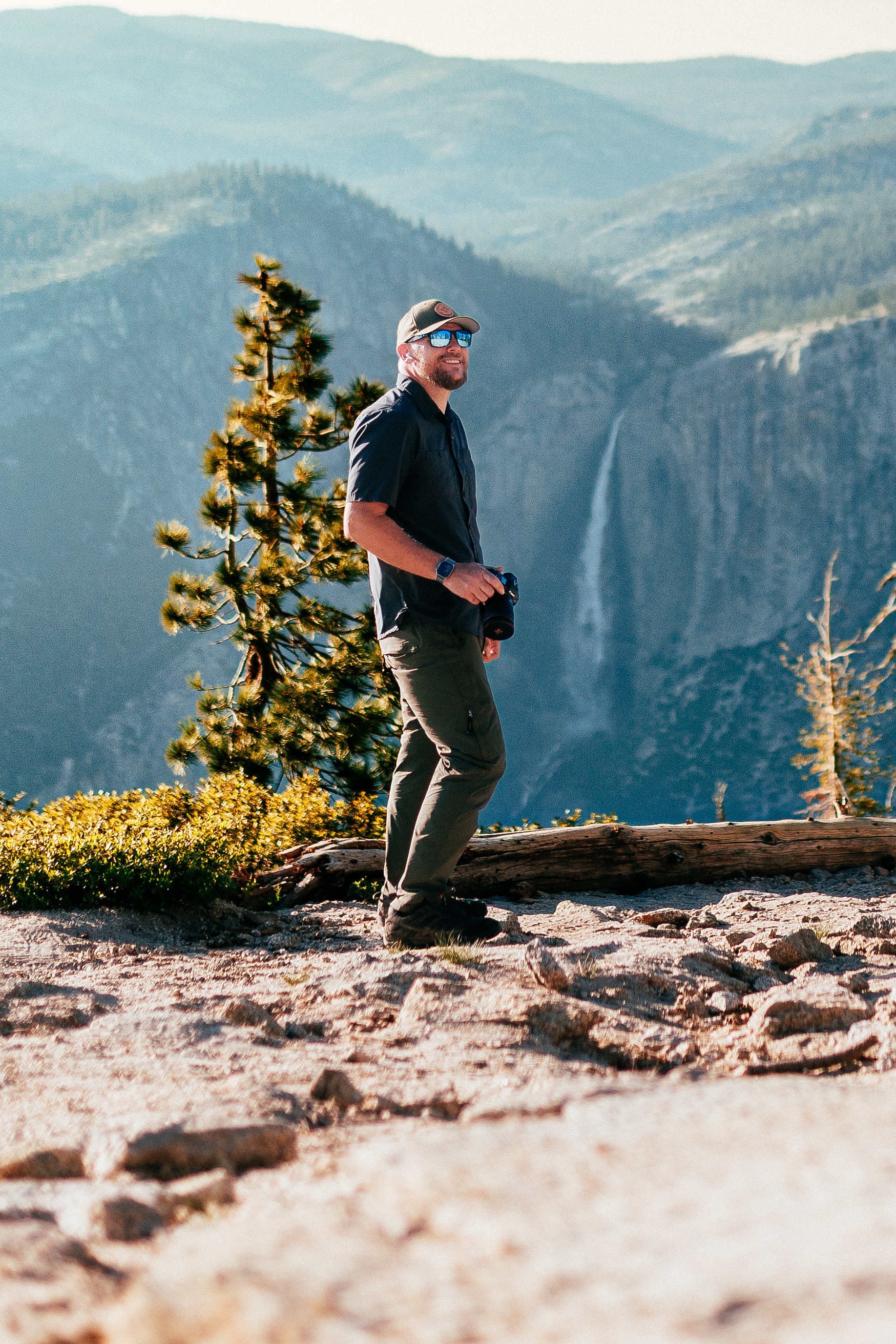 Joseph Blake with a camera on a granite overlook above a waterfall