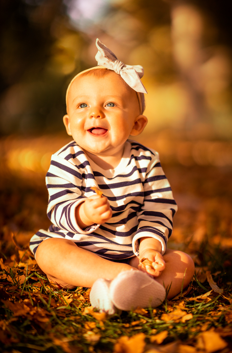 Smiling baby sitting in autumn leaves during a Las Vegas portrait session