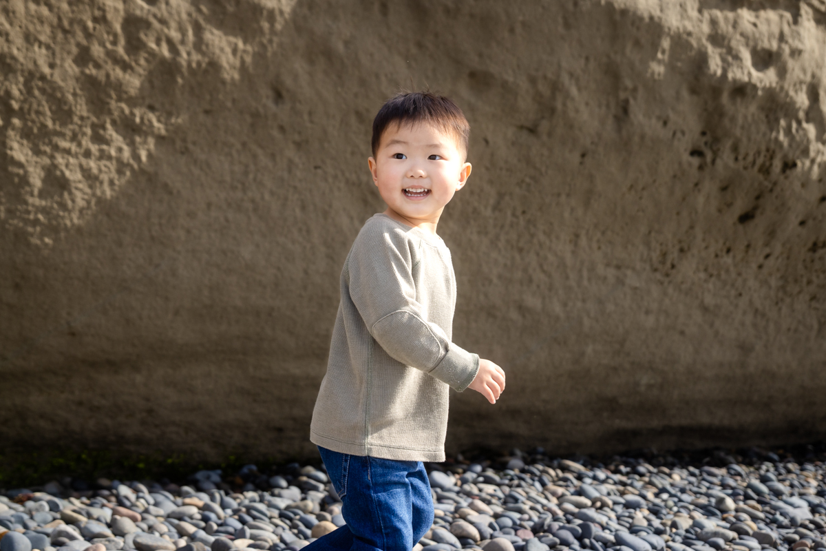 Child in a blue dress photographed in motion on a sandy beach