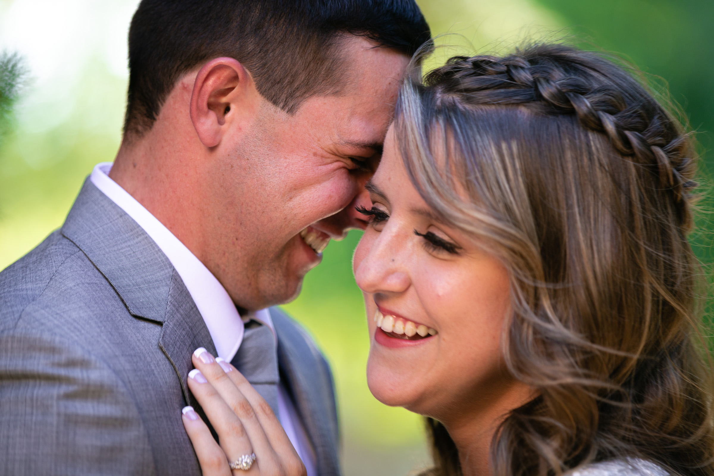 Bride and groom laughing with their foreheads together against a green forest bokeh on Mount Charleston