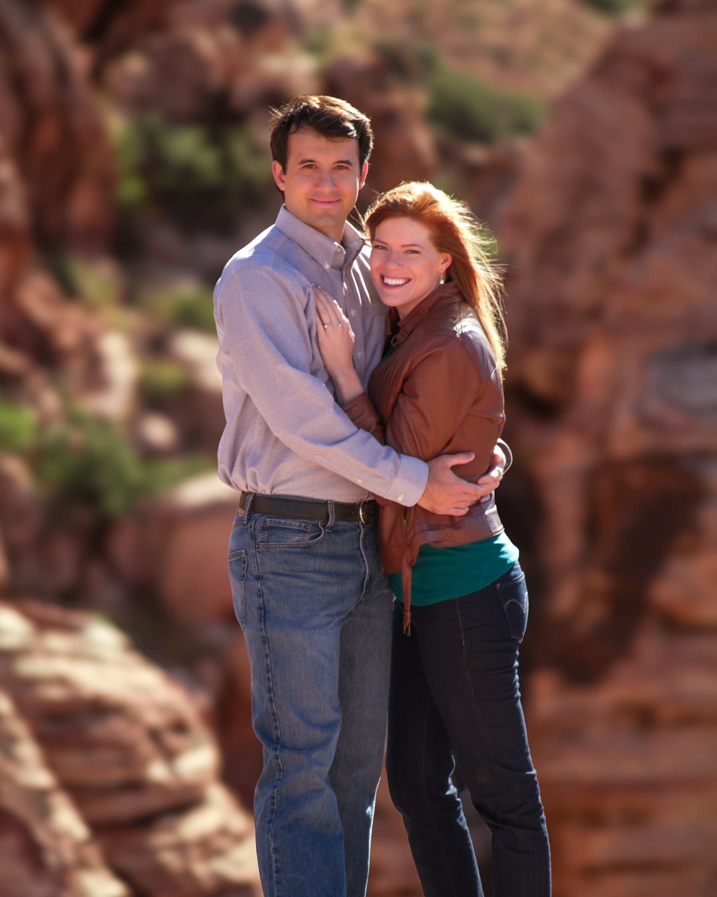 A couple embracing in front of red sandstone cliffs.