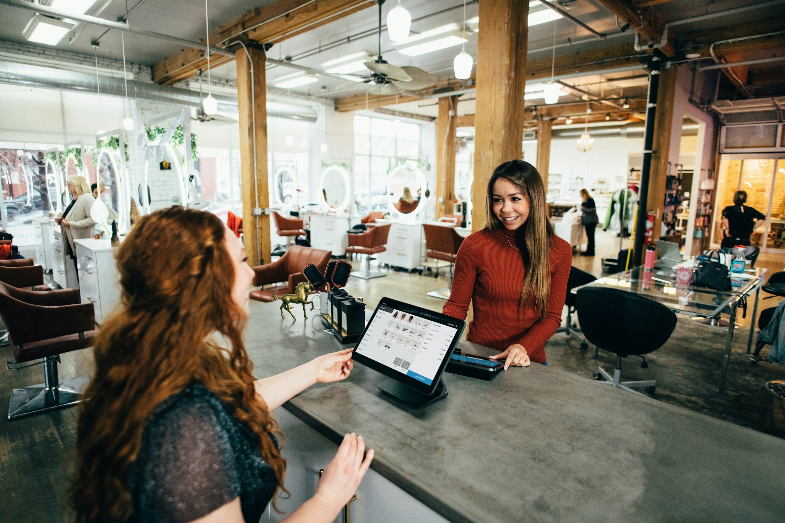 A customer and salon employee discussing a tablet at the reception counter.