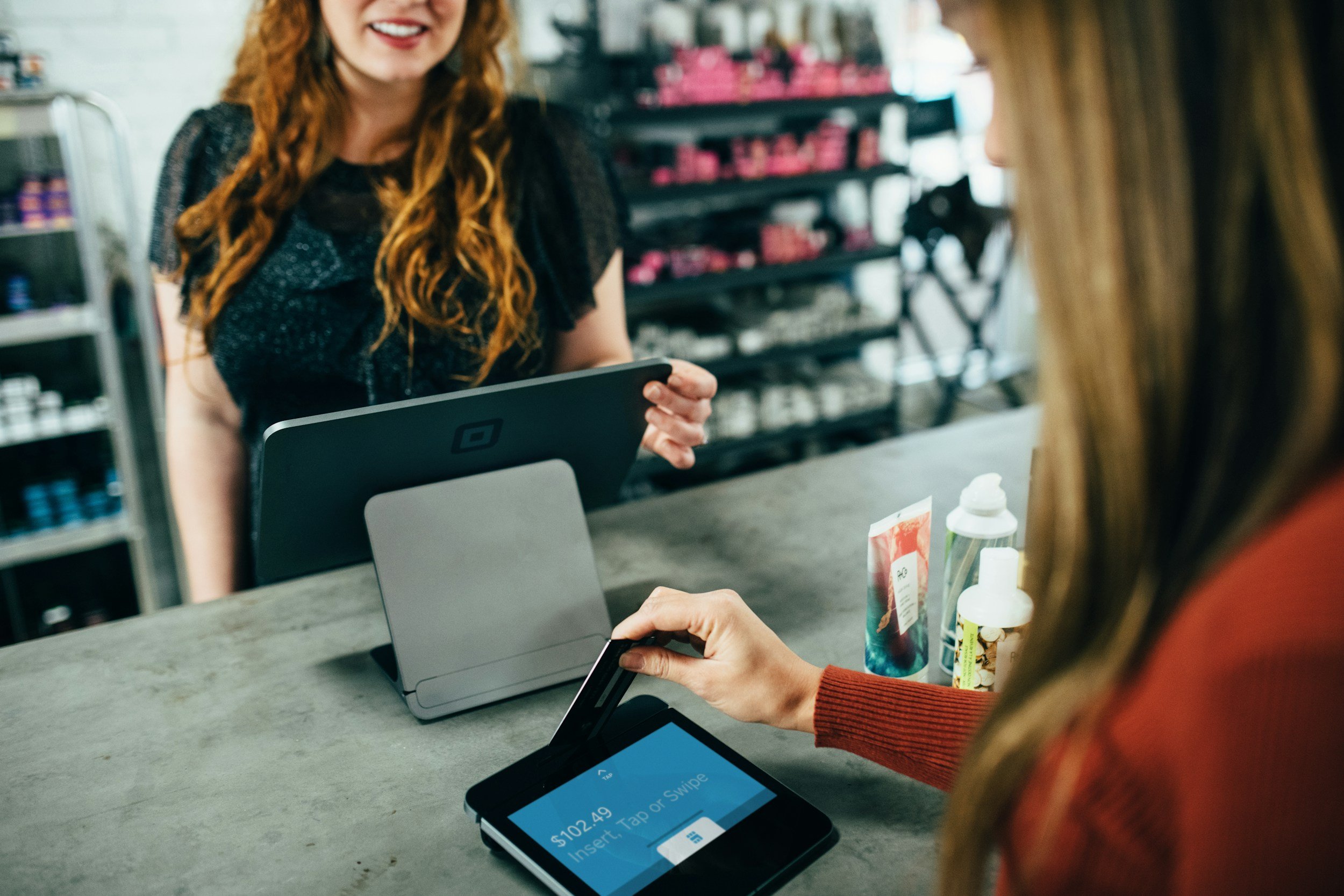 A customer using a payment tablet at a salon counter.