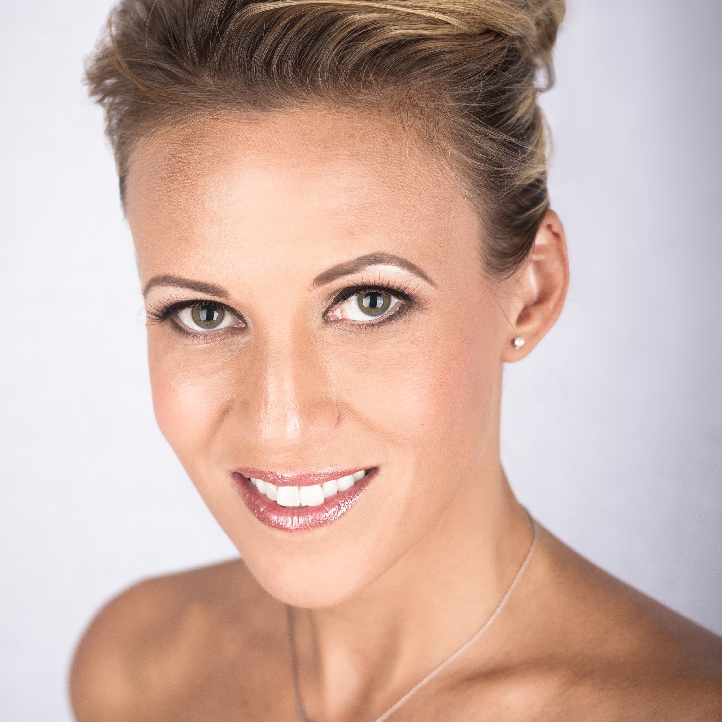 Studio headshot of a smiling woman against a light background.