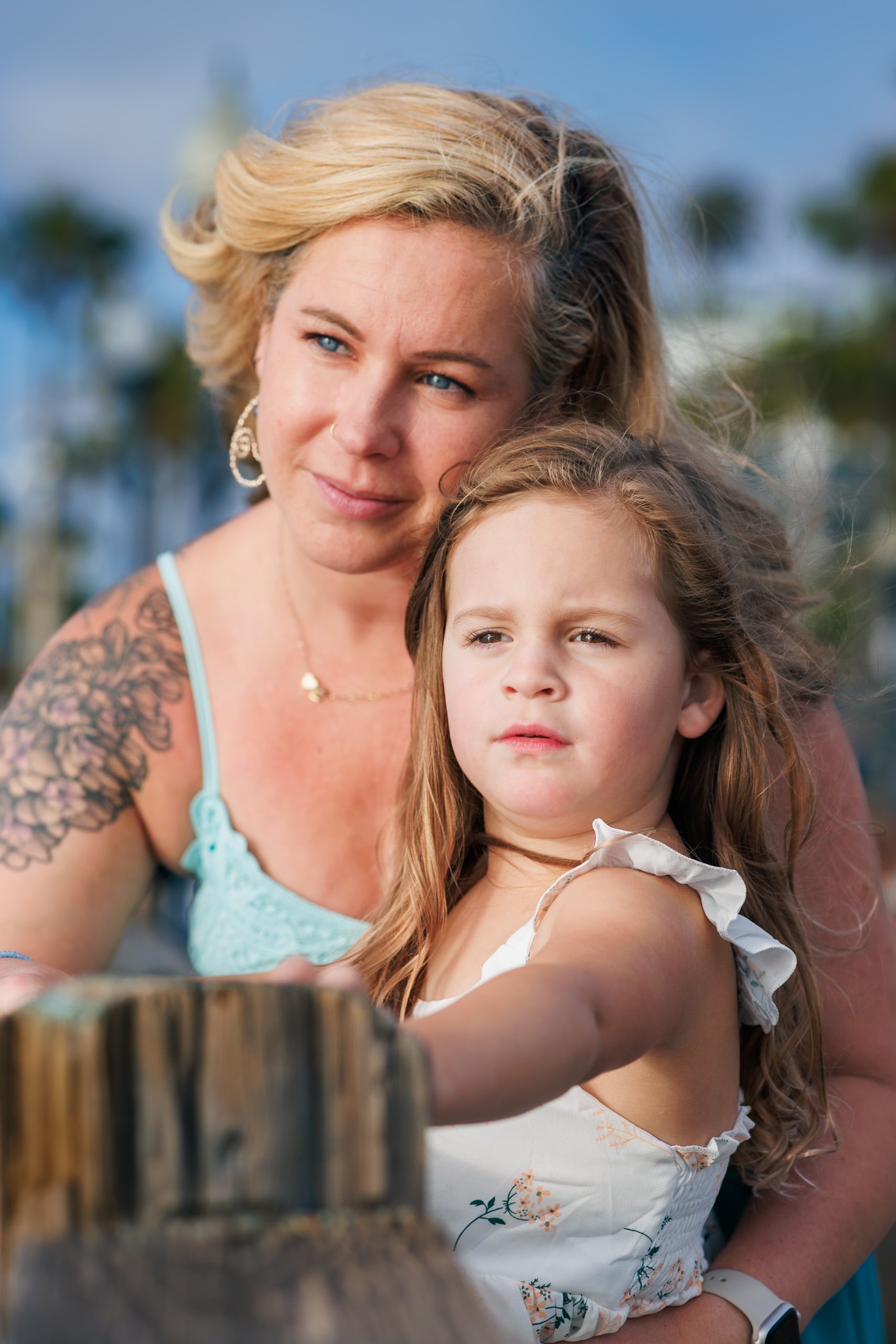 A woman and a young girl sitting close together outdoors.