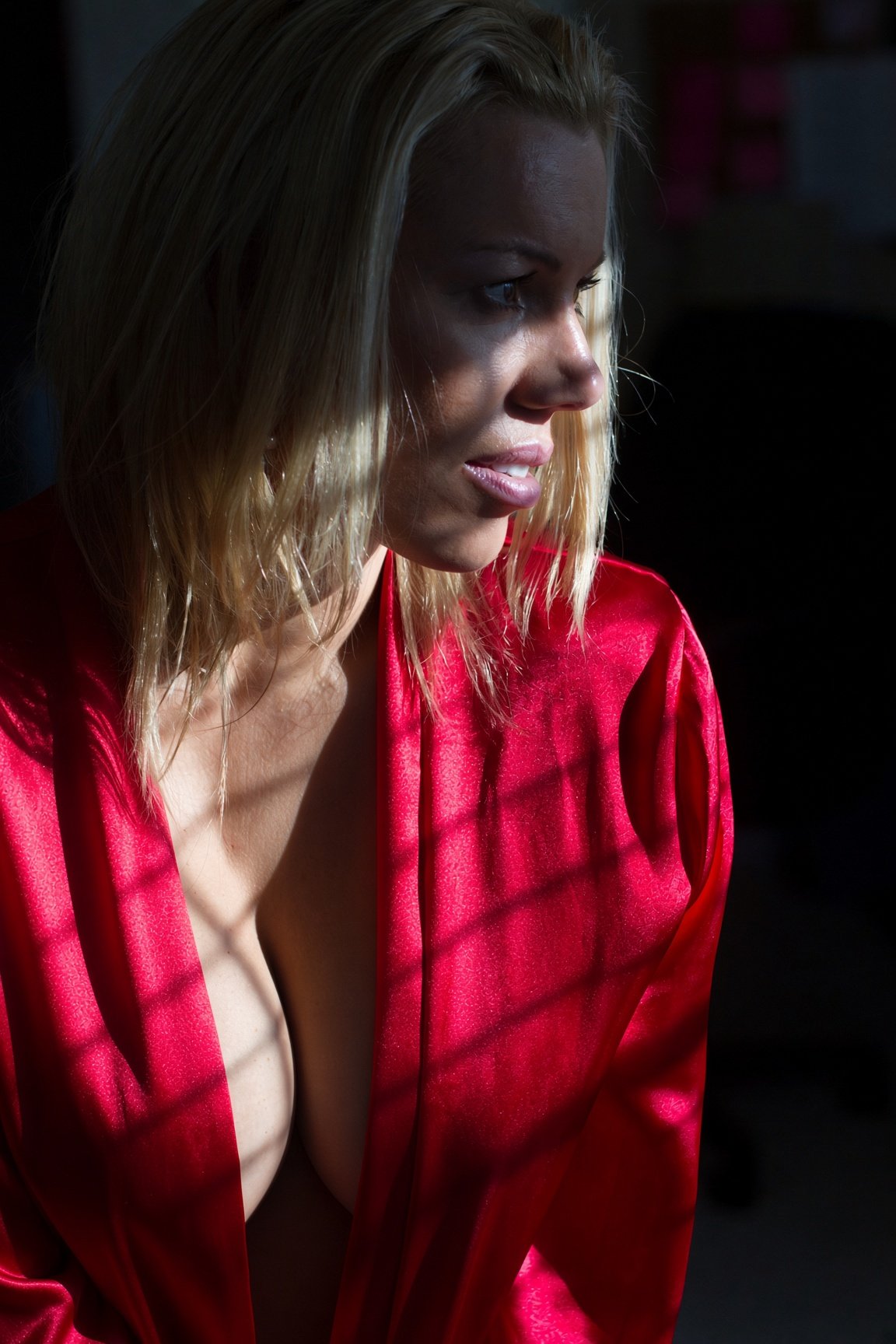 Dramatic window-light boudoir portrait in a red satin robe