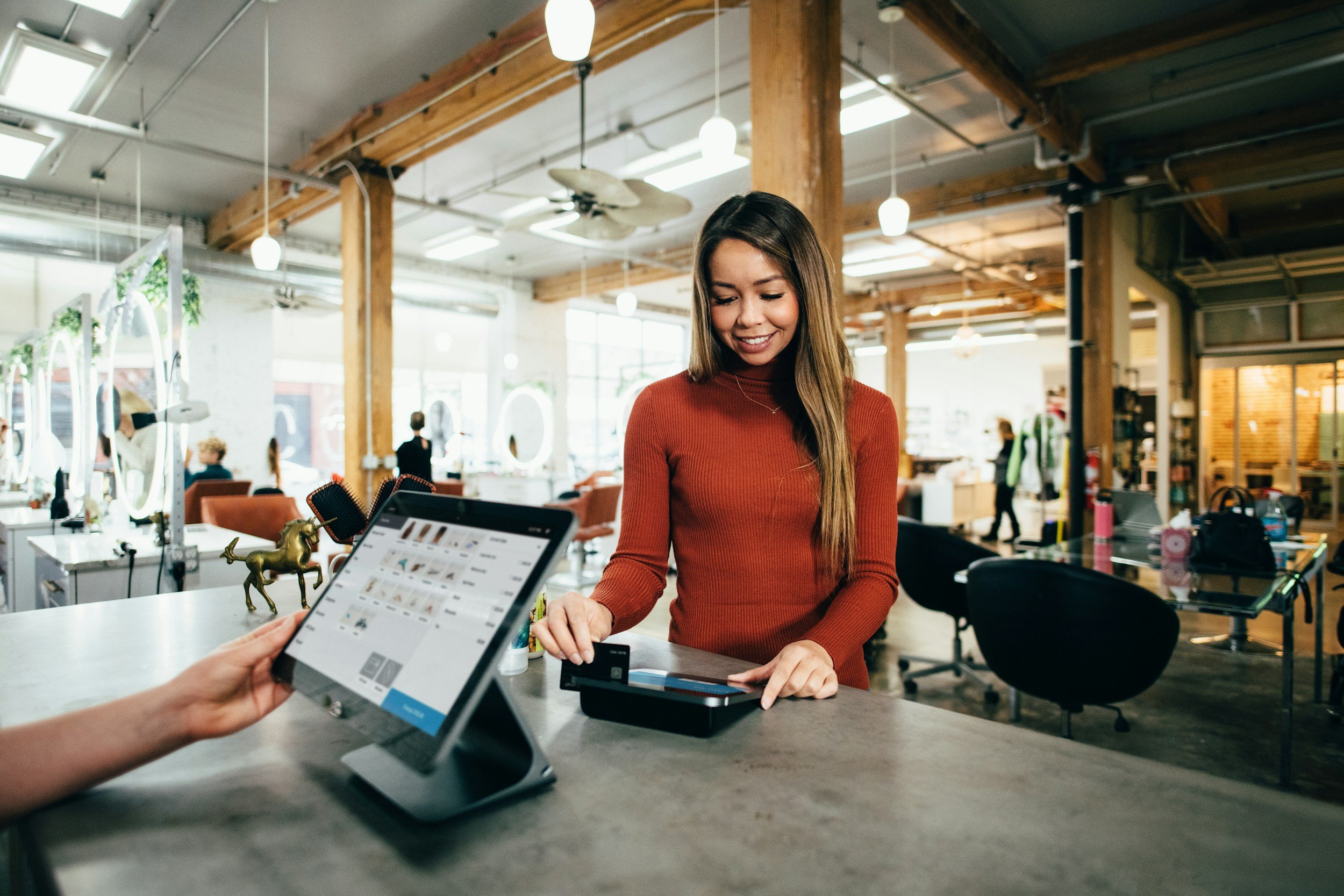 A salon employee using a tablet at the reception counter.